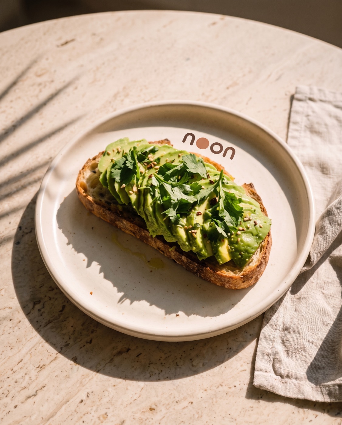 avocado on toasted sourdough with coriander on a noon plate in hard midday light