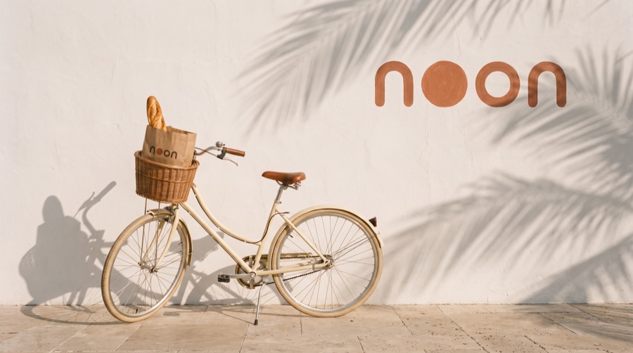 a cream bicycle with a bread basket in front of the noon wall